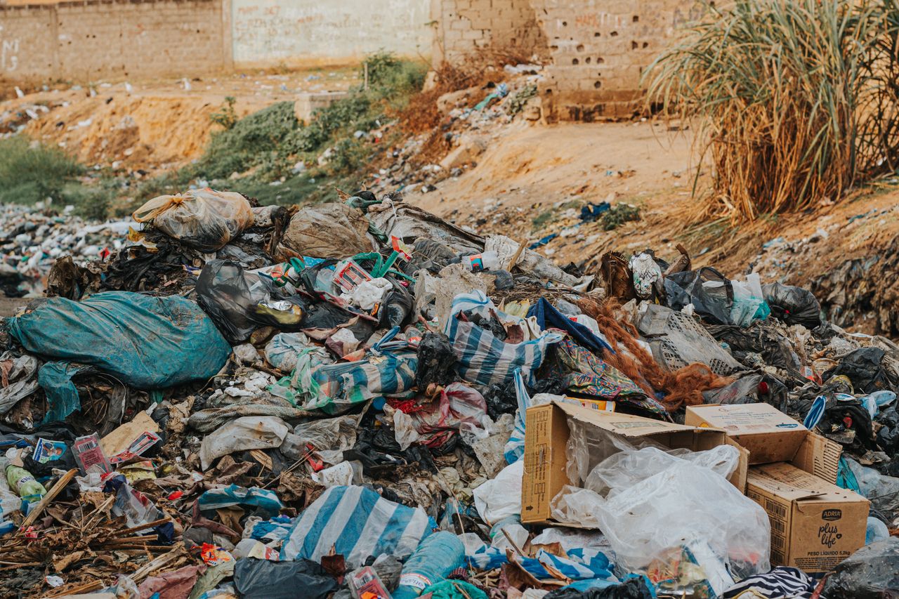 Pile of mixed waste at a sprawling urban landfill, highlighting environmental pollution.